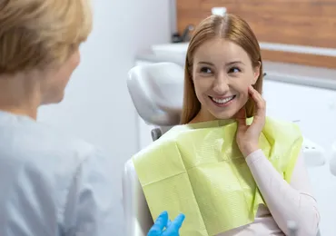 A smiling patient in the dental chair talking to her practitioner