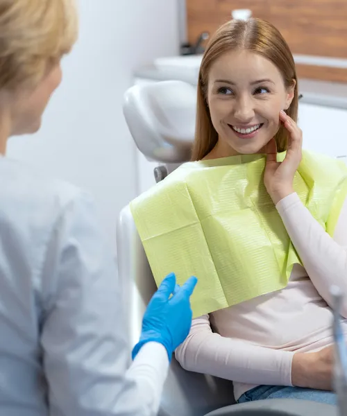 A smiling patient in the dental chair talking to her practitioner